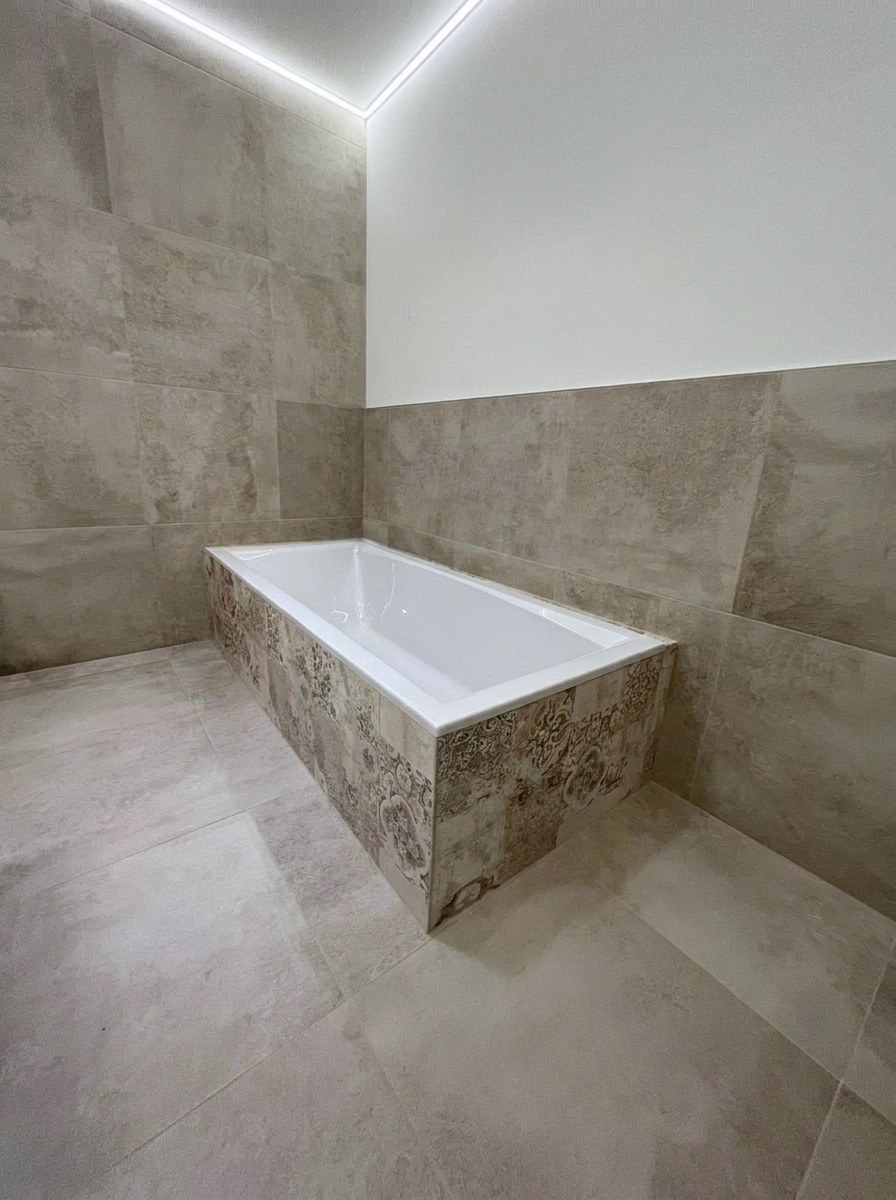 Badewanne mit Naturstein-Verkleidung und Mosaik