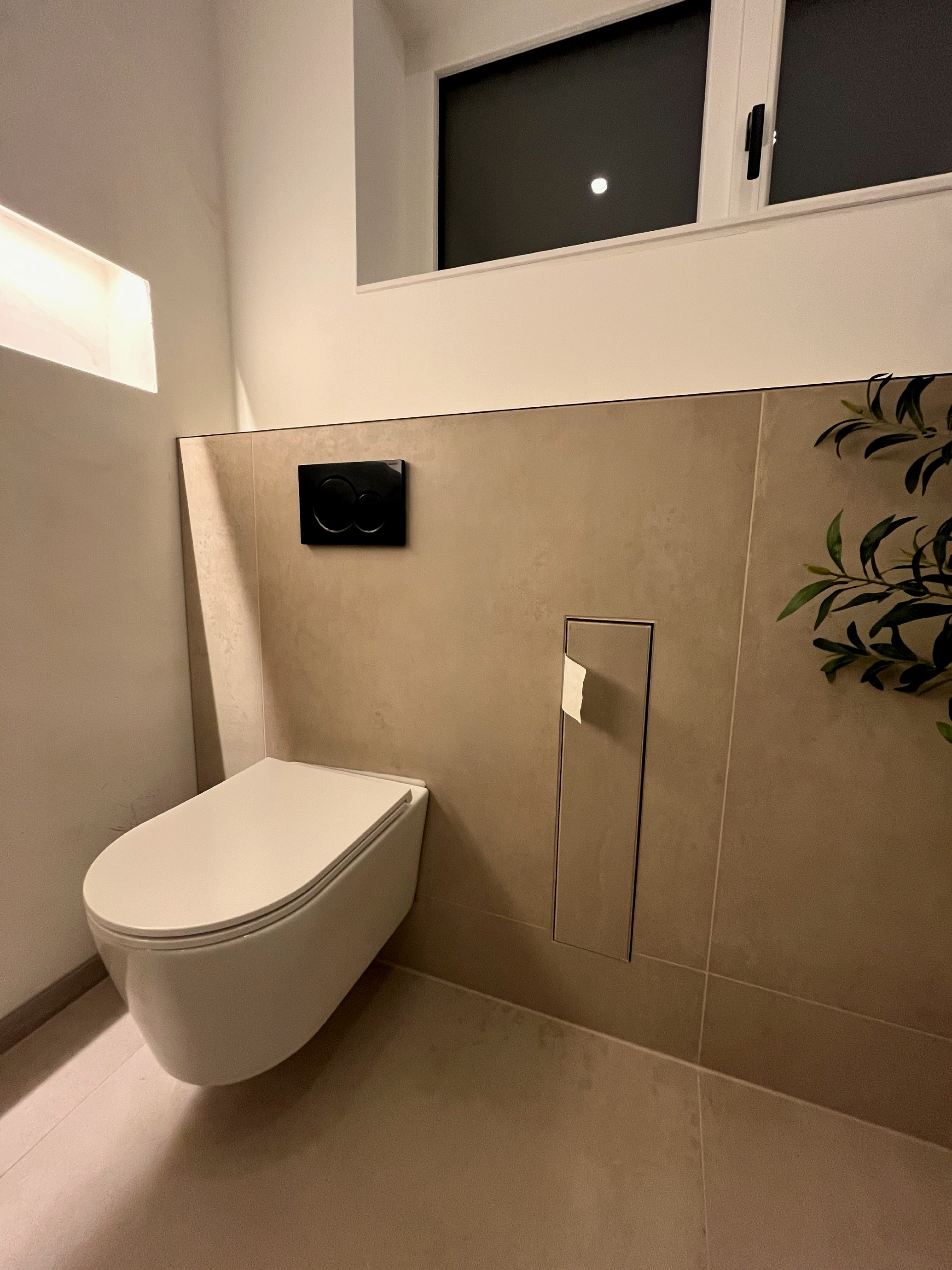 Gaeste-WC mit Steinoptik-Wandfliesen und schwarzem Spuelknopf